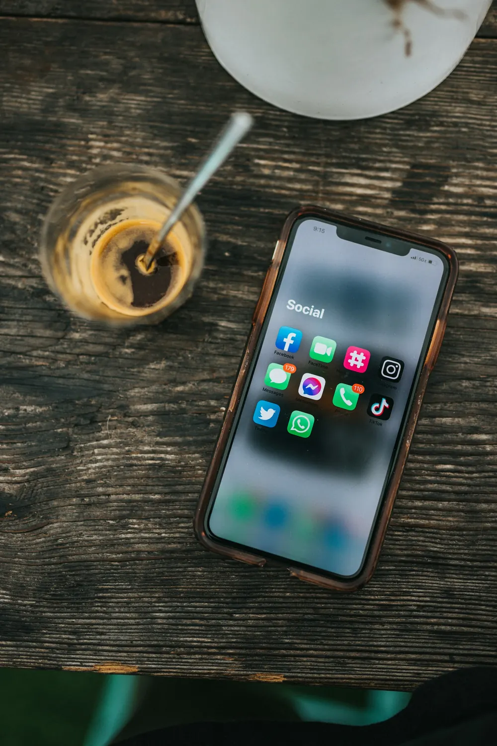 Smartphone displaying social media apps beside a glass of coffee